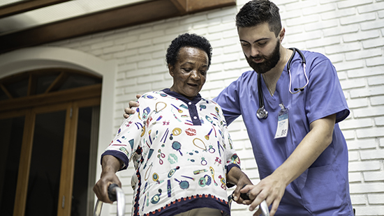 A nurse helping a patient with their walker.